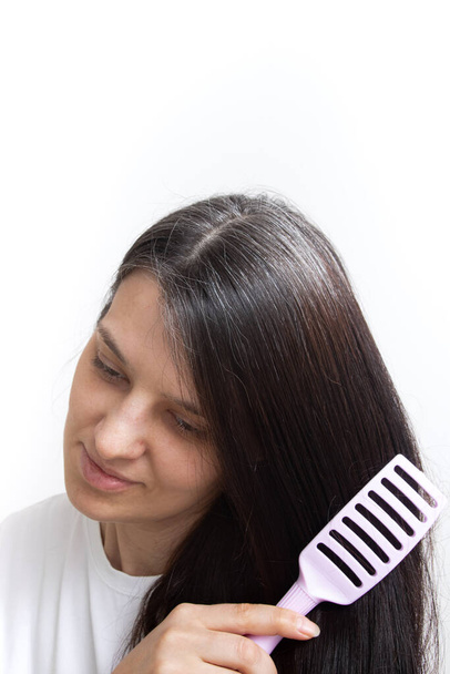 Молодая женщина с седыми волосами расчесывает волосы. Ранние седые волосы концепции, вертикальное фото - Фото, изображение