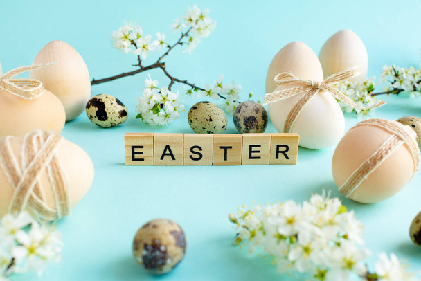 Easter eggs with natural decor and natural flowers. Christian religious Easter holiday. Natural rustic eggs in a string bag on a blue background - 写真・画像