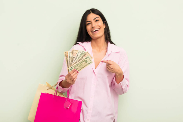 young pretty hispanic woman looking excited and surprised pointing to the side. shopping bags concept - Фото, зображення