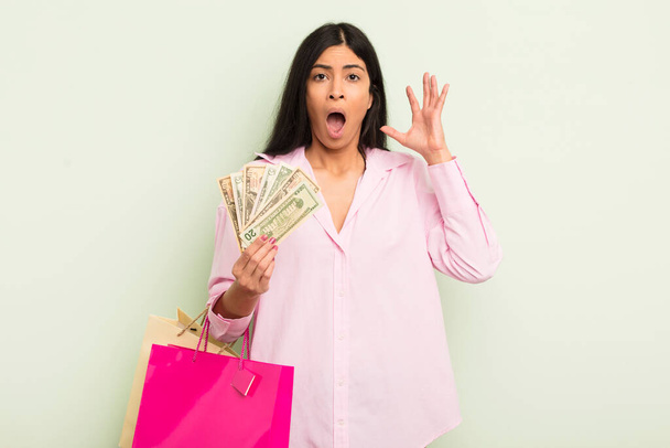 young pretty hispanic woman screaming with hands up in the air. shopping bags concept - Photo, image