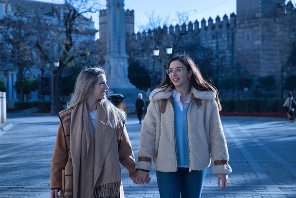 Real couple of young women, holding hands walking in the city, talking in affectionate attitude. Concept lgtbiq+, lesbians, in love, inclusion. - Foto, immagini
