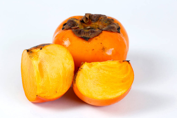 Persimmon, whole and sliced, on white background - Photo, Image