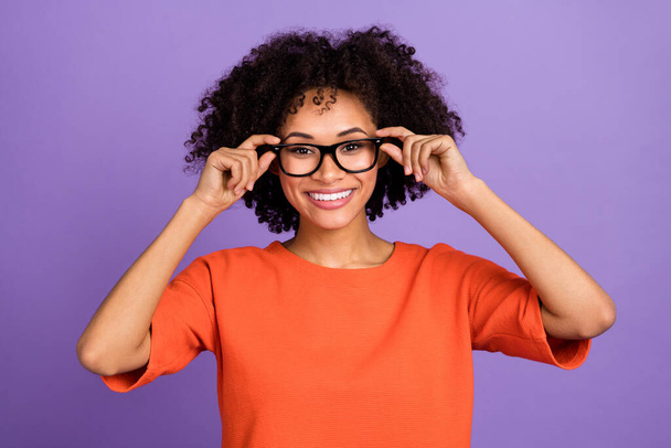 Photo of cute young lady wear eyewear orange t-shirt isolated on violet color background - 写真・画像