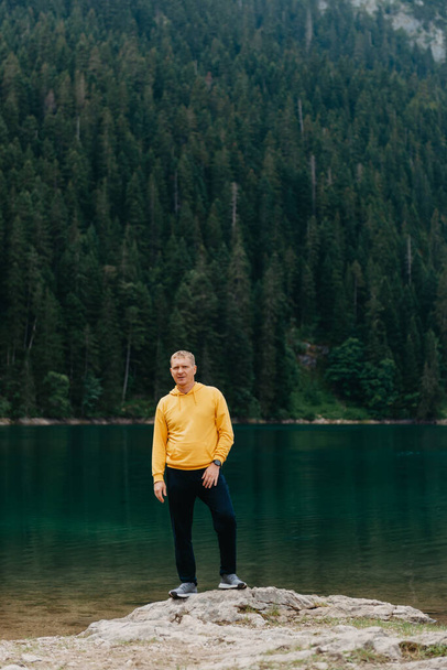 Traveler Man relaxing meditation with serene view mountains and lake landscape. Travel Lifestyle hiking concept summer vacations outdoor. Guy standing near the mountain Lake. A lonely man looks ahead - Foto, Imagen