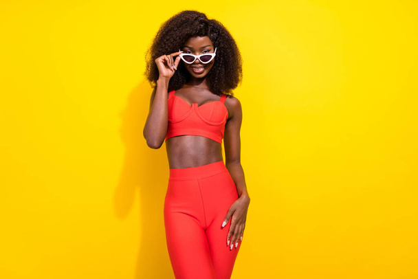 Photo of sweet confident african lady dressed red sexy clothes arm dark glasses smiling isolated yellow color background - Valokuva, kuva