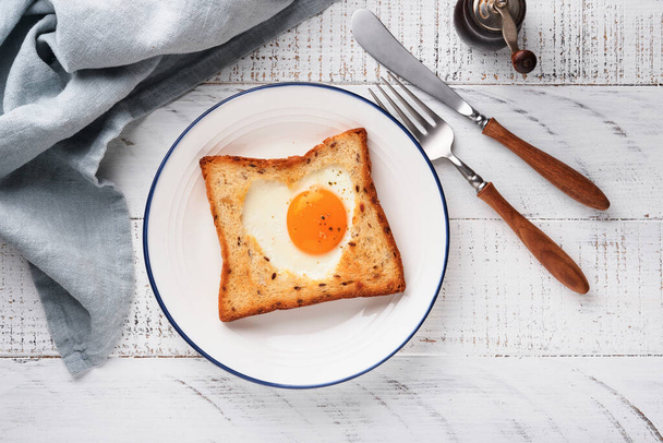 Heart shaped egg with toast and microgreens on light white wooden background, breakfast table top. Valentines day breakfast. Top view. Mock up. - Fotoğraf, Görsel
