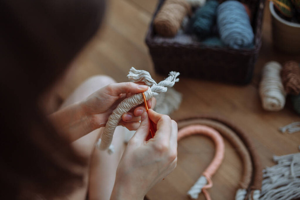 Молода дівчина плете макраме панелі вдома
 - Фото, зображення