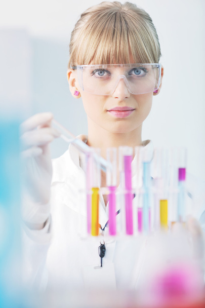 Female researcher holding up a test tube in lab - 写真・画像