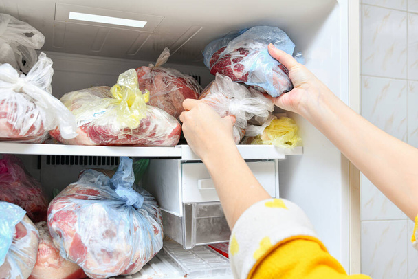 El congelador está lleno de alimentos congelados. La carne, la manteca de cerdo y otros productos semielaborados se presentan en bolsas para su almacenamiento a largo plazo en nevera.. - Foto, imagen