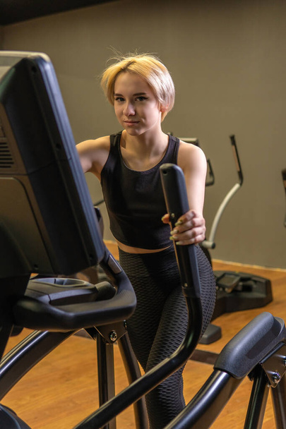 Elliptical trainer young training person, for female gym in running instructor sportswear, room elliptical. Cardio lifestyle living, trainer - 写真・画像