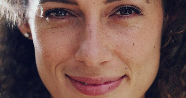 Het gezicht van tevredenheid. 4k video beeldmateriaal een glimlachende volwassen vrouw met krullend bruin haar buiten staan. - Foto, afbeelding