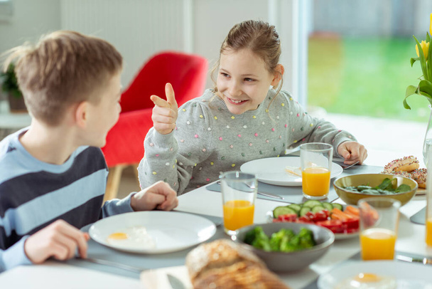 Genç çocuklar okula gitmeden önce evde sağlıklı kahvaltı sırasında konuşurlar. - Fotoğraf, Görsel