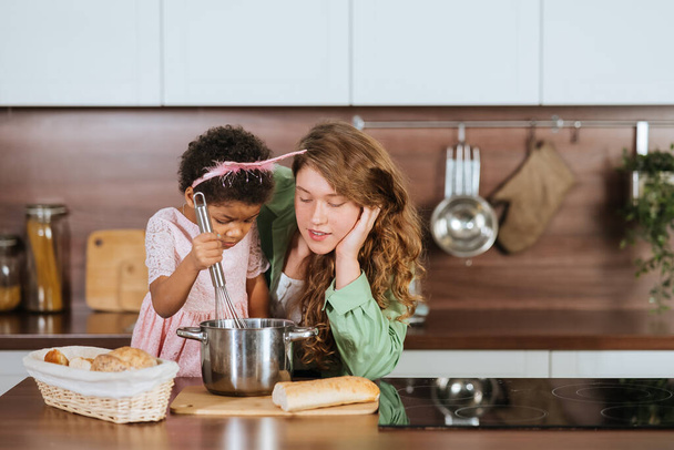gelukkig mama en dochter meisje hebben plezier tijdens het koken in keuken. - Foto, afbeelding