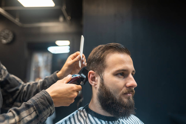 Master in barbershop makes mens haircutting with hair clipper - Fotoğraf, Görsel