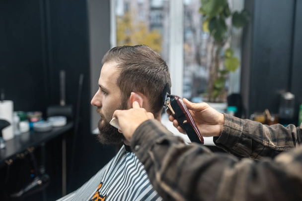 Maestro en barbería hace mens corte de pelo con cortador de pelo - Foto, Imagen