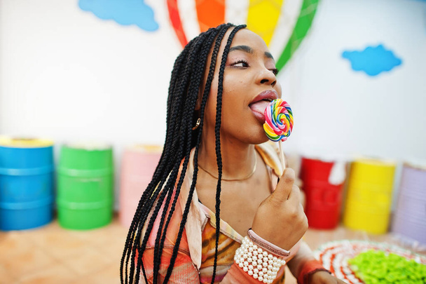 African american millennial lady at candy shop with lolipops. - 写真・画像