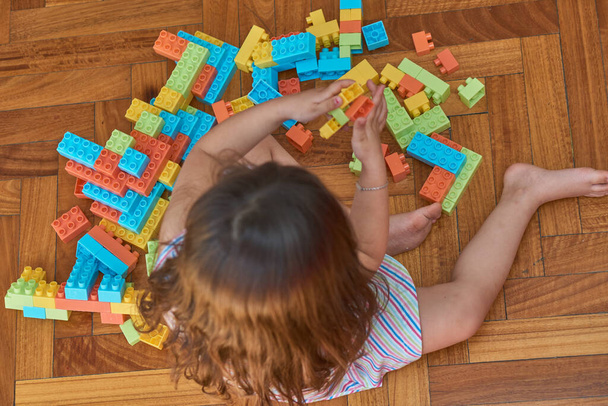 Chica jugando con bloques en el suelo de madera en su habitación - Foto, Imagen