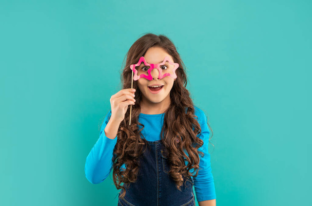 happy teen girl has curly hair hold party accessory of glasses, childhood - Foto, imagen