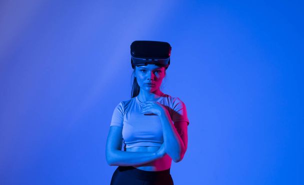 Beautiful brunette woman gamer with a virtual reality glasses ready to play a game in neon light. Modern technologies. - Foto, immagini
