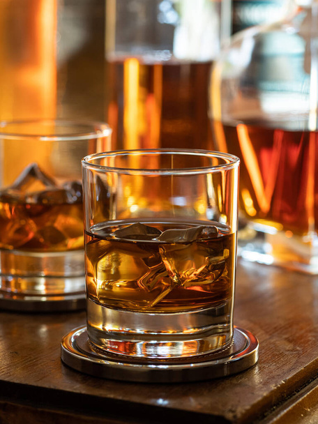 Glass of whisky on the rocks on a wooden bar top - Fotó, kép