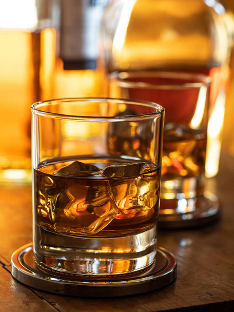 Glass of whisky on the rocks on a wooden bar top - Fotó, kép