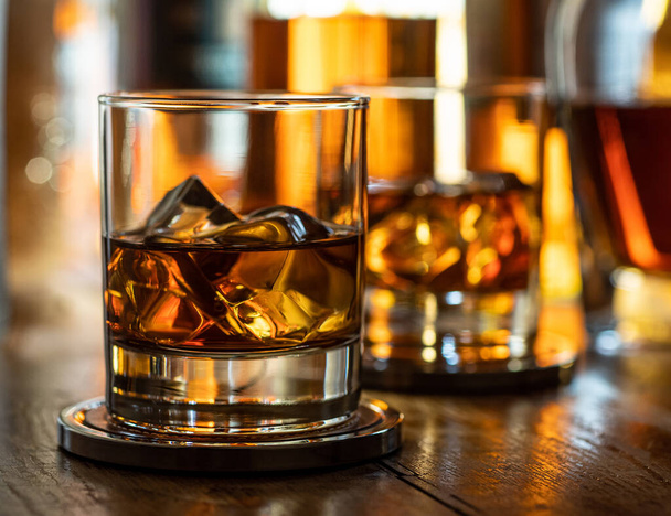 Glass of whisky on the rocks on a wooden bar top - Photo, Image