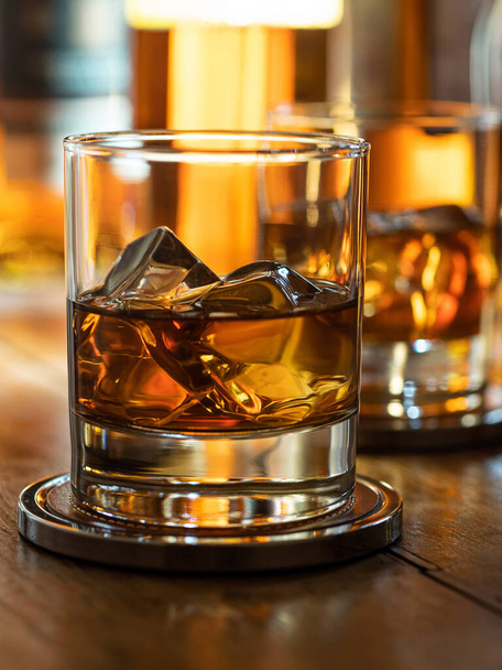 Glass of whisky on the rocks on a wooden bar top - Foto, Bild