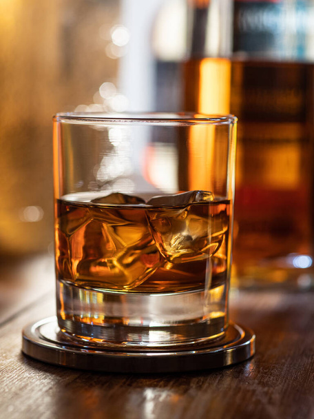 Glass of whisky on the rocks on a wooden bar top - Foto, Imagen