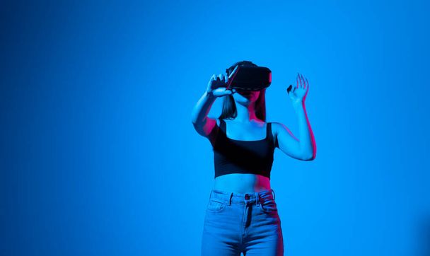 Designer, architect, engineer or developer woman stands in studio wearing VR glasses and swiping, zooming with hands in a virtual space while interacting with objects while working on project. - Photo, image