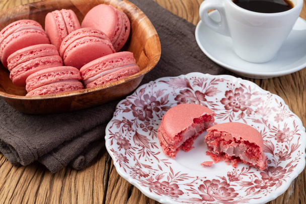 Berry macarons in a bowl with coffee over wooden table. - Photo, Image