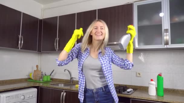 vrouw in geel rubber schoonmaak handschoenen zingt en danst in de keuken - Video