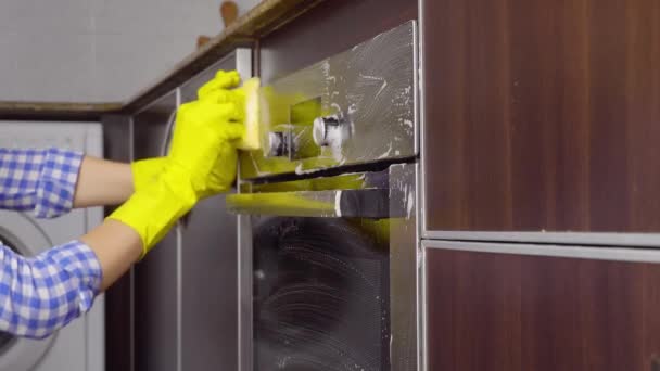femme au foyer en gants jaunes lave cuisinière à gaz dans la cuisine avec éponge. - Séquence, vidéo