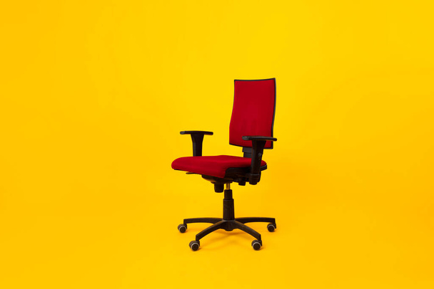 Порожній регульований ергономічний офісний стілець з підлокітниками над жовтим тлом
 - Фото, зображення
