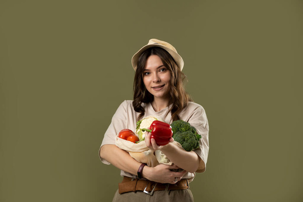 Zero waste concept. Young brunette woman holding reusable cotton shopping mesh bag with organic groceries from a market. Concept of no plastic. Zero waste, plastic free. Sustainable lifestyle. - Foto, immagini