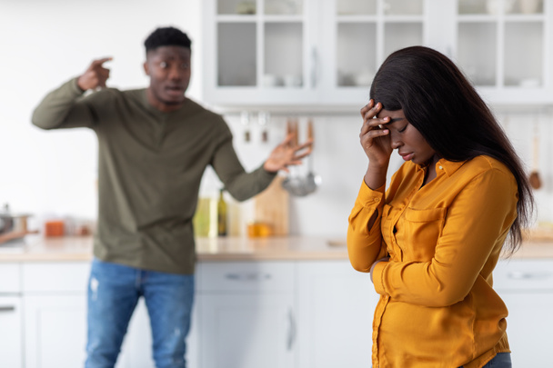 Проблемы в отношениях. Чёрная пара спорит на кухне, мужчина кричит на девушку - Фото, изображение