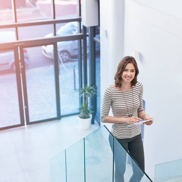 Tecnologia moderna per la donna d'affari moderna. Ritratto di una giovane donna d'affari che utilizza un tablet digitale sulle scale in un ufficio moderno. - Foto, immagini