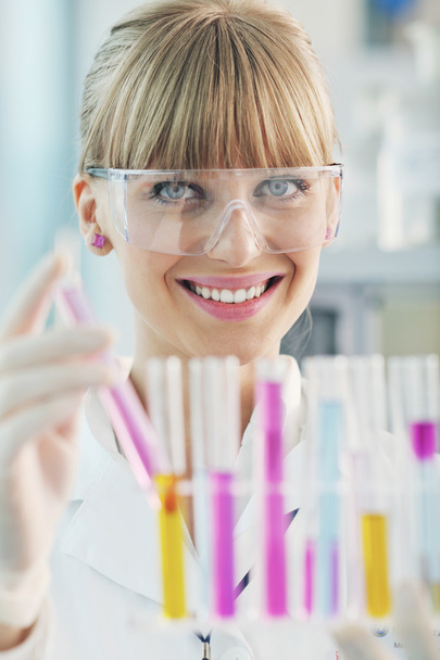 Female researcher holding up a test tube in lab - Фото, изображение