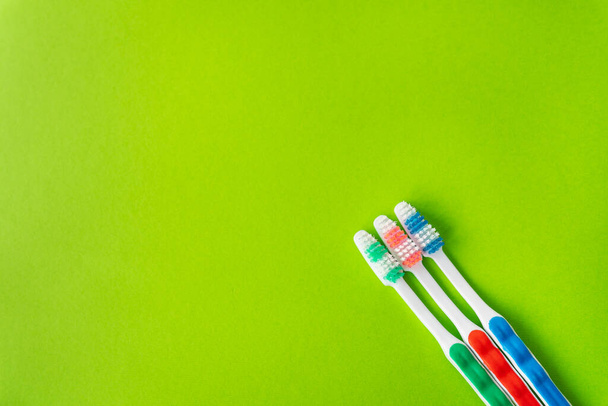Spazzolini multicolori su sfondo verde, il concetto di cura dentale e igiene. Luogo per un'iscrizione - Foto, immagini