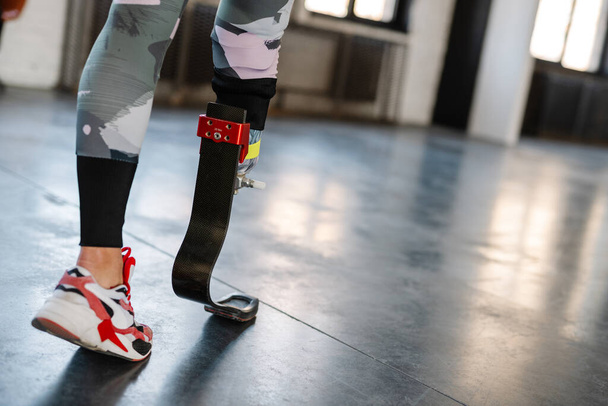 Young sportswoman with prosthesis working out indoors - 写真・画像