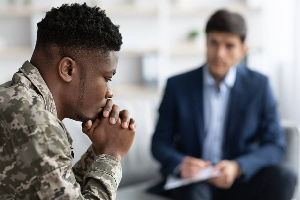Σκεπτικός μαύρος στρατιώτης συζητάει με την κοινωνική λειτουργό. - Φωτογραφία, εικόνα