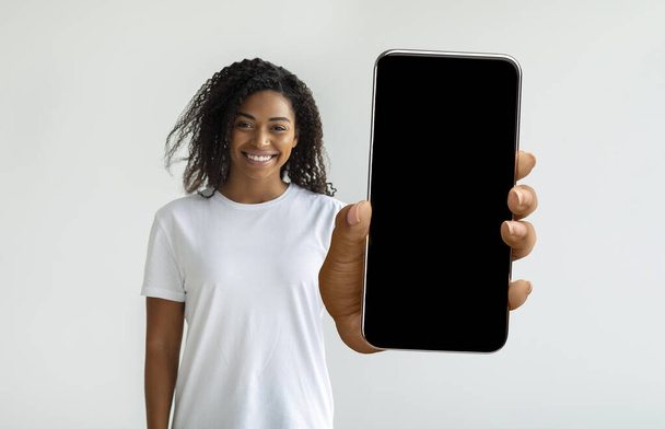 Csinos afro-amerikai nő gazdaság okostelefon üres képernyőn - Fotó, kép