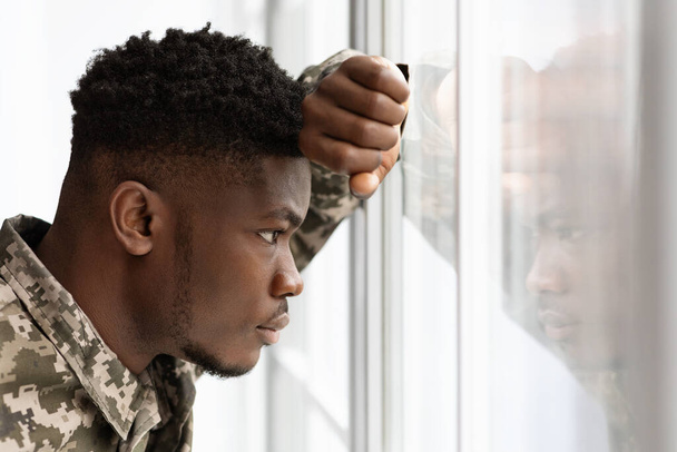 Töprengő afro-amerikai katona néz be az ablakon otthon - Fotó, kép