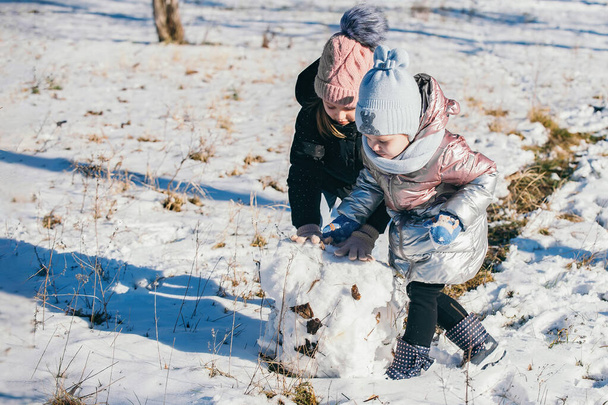 Δύο κορίτσια διαφορετικών ηλικιών διασκεδάζουν και περνούν το χρόνο τους σε χειμερινό περίπατο. - Φωτογραφία, εικόνα