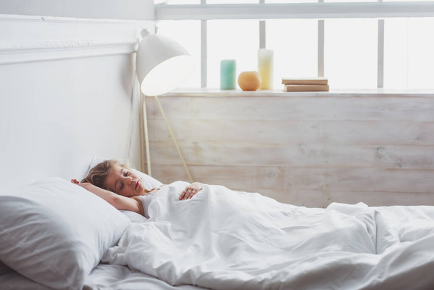 Vista lateral de una linda niña durmiendo en su cama en casa
 - Foto, imagen