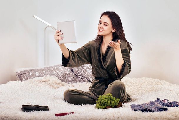 Online setkání pomocí tabletu PC od ženy na posteli s umělou kožešinou. - Fotografie, Obrázek