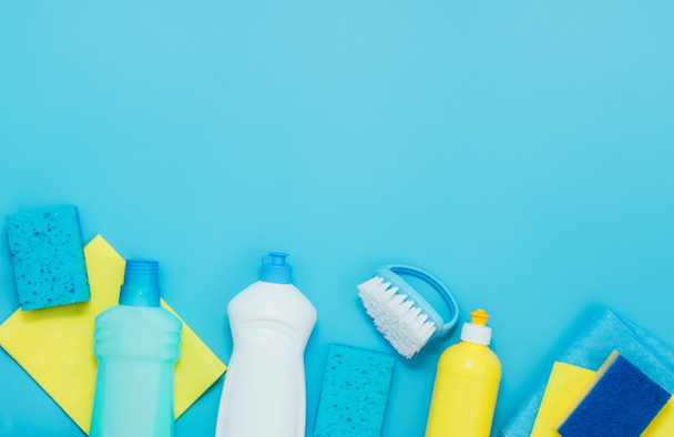 Σετ καθαρισμού απορρυπαντικά χαρτοπετσέτες σφουγγάρια γάντια, μπλε φόντο. Η έννοια του καθαρισμού ή καθαρισμού στο σπίτι υπηρεσίες της εταιρείας - Φωτογραφία, εικόνα