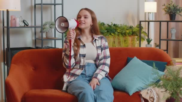 Giovane donna gridare in altoparlante megafono annuncia sconti vendita di immobili a casa sul divano - Filmati, video