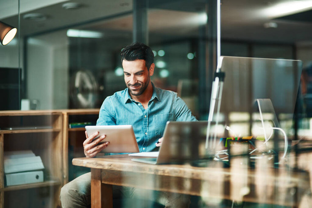 Der digitale Arbeiter erledigt die Dinge. Aufnahme eines jungen Geschäftsmannes mit einem digitalen Tablet an seinem Schreibtisch in einem modernen Büro. - Foto, Bild