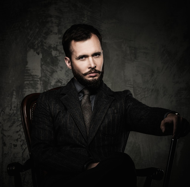 Handsome well-dressed man with walking stick sitting in leather chair  - Photo, Image