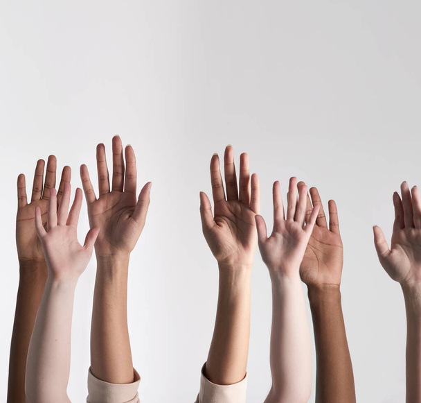 Making their voices heard. Shot of a diverse group of unidentifiable people holding their hands up against a white background. - Фото, зображення
